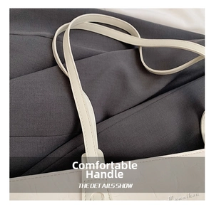 Detail showing the cracked texture of the white tote bag and refined handle stitching