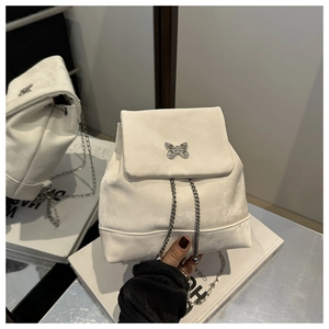 Detail of white suede mini backpack featuring a metallic butterfly clasp and chain straps