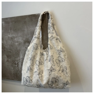 Close-up of white canvas tote bag with grey butterfly print and lace plush texture