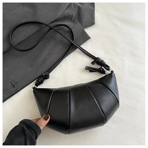 Détail du sac croissant noir en cuir mat souple avec bandoulière à nœud décoratif