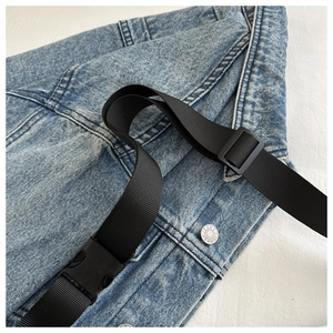 Detail of blue denim hobo bag featuring nylon strap, plastic buckle and metal jeans button