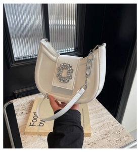 Détail du sac demi-lune en cuir blanc avec une élégante boucle carrée en strass brillants