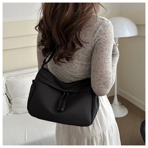 Detail of black minimalist tote bag showing woven zipper pulls and fabric texture on model