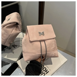 Detailed view of pink suede backpack featuring silver butterfly charm and chain straps