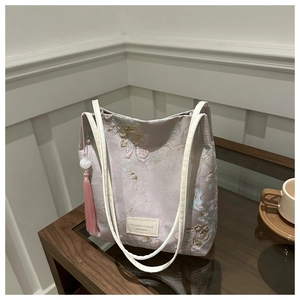 Détails de broderie florale sur sac en satin lilas avec pendentif à pampille rose