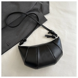 Détail d'un sac croissant noir avec texture cuir plissée et bandoulière à nœud élégant