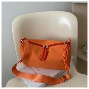 Detailed shot of orange nylon crossbody bag with chunky plastic chain and woven zipper pull