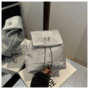 Detail of silver velvet mini backpack with a butterfly metal clasp and chain straps