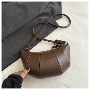 Détail du sac croissant marron foncé avec texture plissée et nœud sur la bandoulière