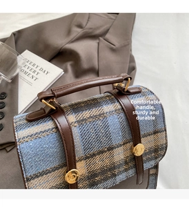 Detail of British style plaid backpack with brown leather handle and gold hardware buckles