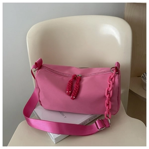 Detail of bright pink nylon pillow bag with plastic chain on minimalist white chair