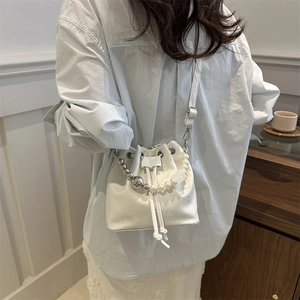 White bucket bag with beaded pearl handle shown from the back perspective on a model