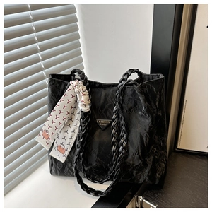Detail der schwarzen Shopper-Tasche mit geflochtenen Riemen, Seidentuch und Faltentextur