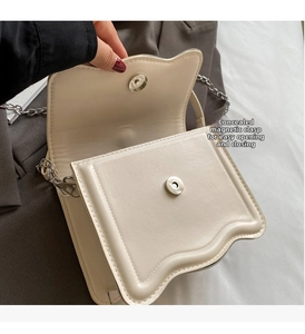 Detailed view of white mini crossbody bag featuring a wave flap and invisible magnetic closure