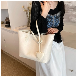 Detail of cream tote bag with leather pleated texture and heart pendant charm