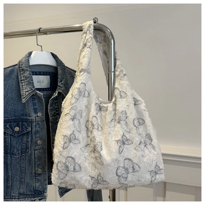 Detail of white canvas tote bag featuring textured grey butterfly prints and lace fabric