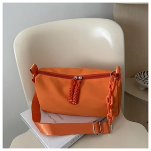 Detail of bright orange nylon cylinder bag with woven zipper pull and chunky chain