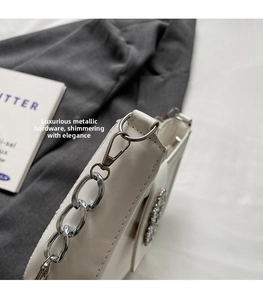 Gros plan d'un sac à main blanc en cuir avec chaîne argentée et détails en strass