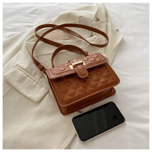 Detail of a brown quilted crossbody bag featuring a classic gold square metal clasp closure