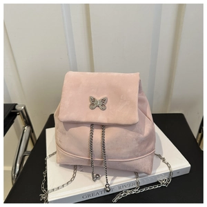 Detail of pink velvet backpack featuring silver butterfly hardware and metal chain straps