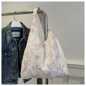 Detail of white canvas tote bag with pink butterfly prints and frayed tassel textures