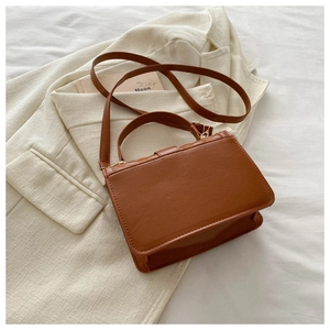 Detail of caramel brown PU leather crossbody bag with top handle and gold hardware