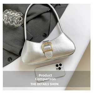 Detail of silver metallic baguette bag with large gold buckle and smartphone for scale