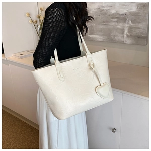 Close-up of cream-white tote bag with pleated texture and a heart-shaped pendant