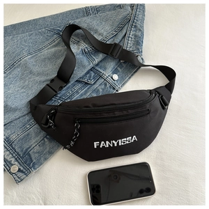 Detail of black nylon crescent bag with FANYISSA logo and adjustable strap on fabric background
