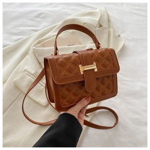 Detail of caramel brown quilted faux leather bag with golden metallic clasp buckle