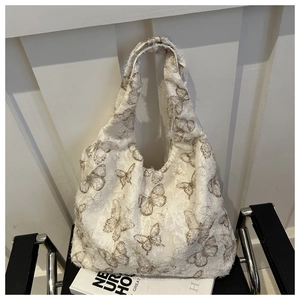 Detail of white canvas tote bag with brown butterfly embroidery and frayed edges finish