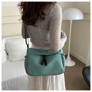 Detail of green tote bag with side pleated pockets and adjustable black strap
