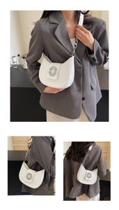 Détail d'un sac demi-lune blanc avec boucle en cristaux et bandoulière en chaîne