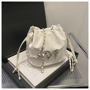 Detail of cream drawstring bucket bag with silver butterfly and leather chain strap