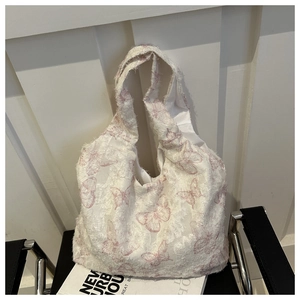 Detail of white canvas tote featuring pink butterfly jacquard and trendy frayed edges