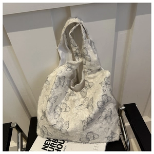 Detail of white canvas tote bag featuring grey butterfly prints and frayed lace texture