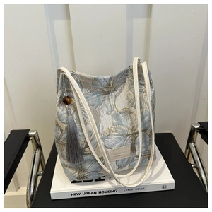 Détail du sac cabas en jacquard floral avec logo en cuir et pendentif à pompon gris