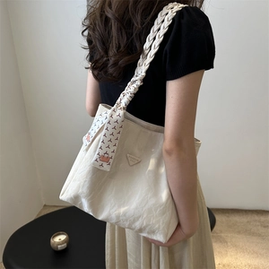 Beigefarbene Handtasche mit geflochtenen Griffen und gemustertem Seidenschal im Studio