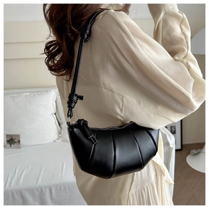 Detail of black half-moon dumpling bag with knotted shoulder strap worn on shoulder