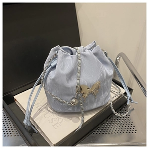 Gros plan d'un sac seau bleu clair avec boucle papillon argentée sur boîte de luxe