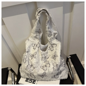 Close-up of plush off-white tote bag with black butterfly patterns on a leather chair