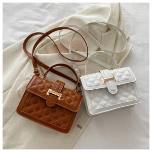Detail of rhombic quilted PU leather handbags with elegant gold metal buckles in brown and white