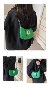 Détail du sac demi-lune vert avec boucle en cristal et bandoulière chaîne argentée