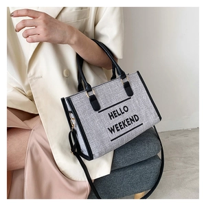 Detail of canvas tote bag with black leather straps and Hello Weekend lettering