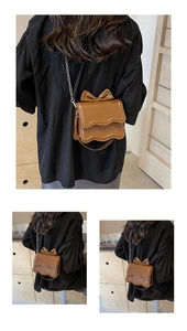 Detailed view of a brown crossbody bag with a wavy flap and large decorative bow detail
