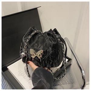 Détail d'un sac seau plissé noir orné d'un papillon métallique à effet liquide argenté