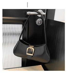 Detail of a vintage black patent leather baguette bag with a golden square buckle accent