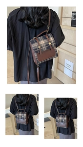 Detail of plaid fabric and brown leather backpack with golden metal buckles and handle