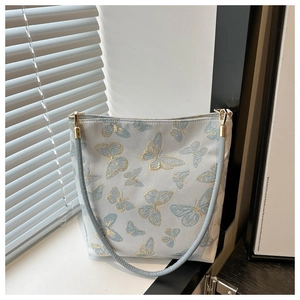 Détail du sac bandoulière bleu clair avec broderie papillon dorée et finitions soignées