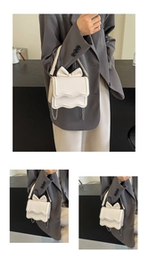 Detail of cream white handbag featuring 3D bow decoration and wavy edge design